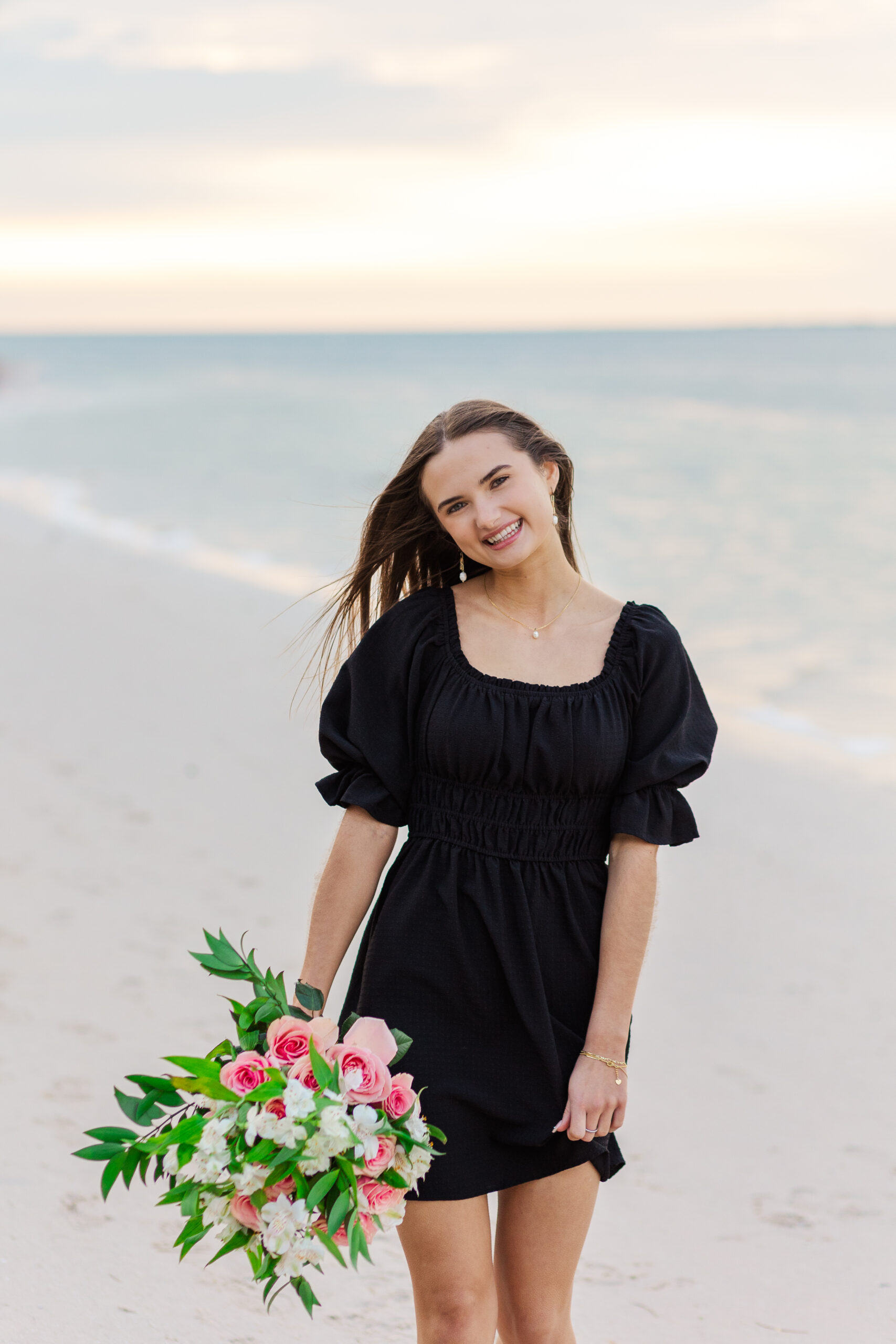 High School Senior, walking on a beach with flowers. This senior wanted her session at a beach. She loves flowers, so she brought flowers because they make her happy.